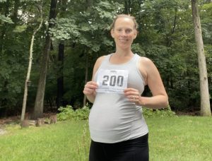 woman holding running bib running while pregnant