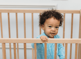 toddler standing in his crib, not sleeping because he is ready to drop naps