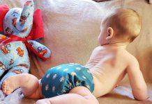 Infant crawling wearing just a cloth diaper, green with octopus pattern on it.