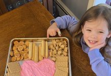 little girl smiling next to her super easy valentine's dessert board